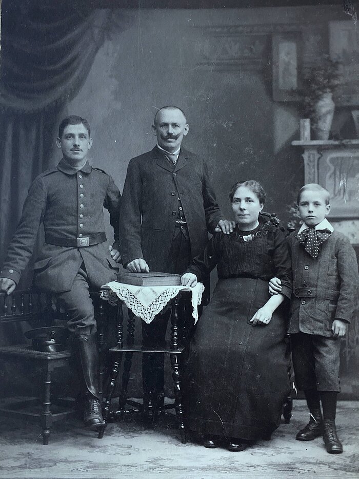 Zu sehen ist ein Porträt der vierköpfigen Familie von Jakob Christian Adam. Es handelt sich um ein Schwarz-Weiß-Bild aus der Vorkriegszeit. 