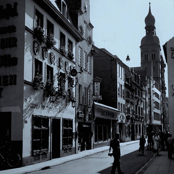 Auf dem Bild ist ein Laden im Zentrum von Bonn mit dem Schriftzug C.J. Adam zu sehen. Das schwarz-weiße Bild ist aus den 80er Jahren.